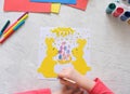 Child making card with Easter bunnies from colorful paper. Applique. Handmade. Project of children`s creativity, handicrafts,