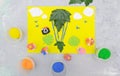 Child making card from paper, plasticine and natural leaves. Air balloon, clouds, birds, flowers... Inspiration for children.