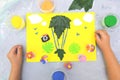 Child making card from paper, plasticine and natural leaves. Air balloon, clouds, birds, flowers... Inspiration for children.