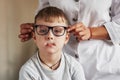 Child making faces to the camera. Kid sitting in the doctor office and trying new blue glasses Royalty Free Stock Photo