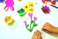 Child making funny crafts from paper and clay, plasticine. Flowers and hearts as gift for Mothers day, Birthday or Valentines