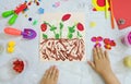 Child making harvesting of fresh red strawberry fruit from paper and plasticine, applique. Children development leisure learning