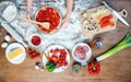 Child making pizza with pizza ingredients, tomatoes, salami and mushrooms on wooden tabletop