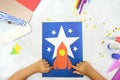 Child making rocket and stars from paper. Creative children play with craft. The space theme development of children. School