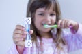 Girl kid measures time while brushes her teeth. Healthy habits, dentalcare concept. Close up