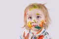 The child messy painted his face and clothes with paint. Children`s pranks