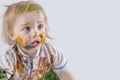 The child messy painted his face and clothes with paint. Children`s pranks. Free space for advertising