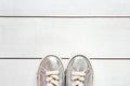 Child metallic silver sneakers on white wood board background texture with copy space. White sneakers for girls. Top view Royalty Free Stock Photo