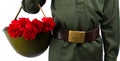 Child in military uniform and a belt, holding a helmet with carnations