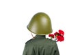 child in military uniform and a helmet stands with his back, holding a carnation, in front of a white background