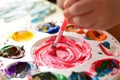 Child mixing paint on a palette of colorful paint