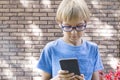 Child with mobile phone outdoors. Boy looks at the screen, use application, plays. City background. School, people Royalty Free Stock Photo