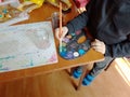 Child moistens the brush in a palette with multi-colored paints. Children`s creativity and painting science. Creative activity of