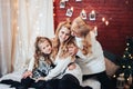 Child with mom and grandmother are seated hugging on the big bed. Christmas mood. Against the background of a brick wall with Royalty Free Stock Photo