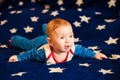 Child 6 months old and smiling at home on a blue blanket of the starry sky