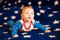 Child 6 months old and smiling at home on a blue blanket of the starry sky