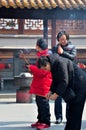 Child, mother and grandmother burn incense at temple: Shanghai, China