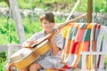 Child musician playing guitar. Kids music. Stylish little boy child wearing a summer shirt having fun on backyard. Happy Royalty Free Stock Photo