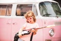 Child musician playing the guitar like a rockstar on pink background in neon light. Caucasian little boy learning to Royalty Free Stock Photo