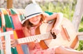 Child musician playing guitar. Stylish little child girl wearing a summer dress having fun on backyard. Summer activity Royalty Free Stock Photo