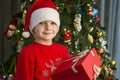 Child near Christmas tree with gift box. Cute little boy is standing near Christmas tree with gift. Merry Christmas and Happy New Royalty Free Stock Photo