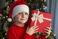 Child near Christmas tree with gift box. Cute little boy is standing near Christmas tree with gift. Merry Christmas and Happy New Royalty Free Stock Photo