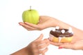 Child obesity concept with little girl hand choosing a sweet and unhealthy doughnut instead of a fruit