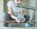 Child open water tap. Kitchen faucet. Glass of clean water. Pouring fresh drink. Hydration. Healthy lifestyle. Water quality check Royalty Free Stock Photo