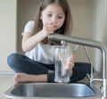 Child open water tap. Kitchen faucet. Glass of clean water. Pouring fresh drink. Hydration. Healthy lifestyle. Water quality check Royalty Free Stock Photo