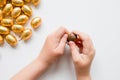 Child opening chocolate egg with gold foil candy on white background Royalty Free Stock Photo