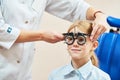 Child optometry concept. Young girl with phoropter during sight testing