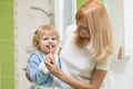 Child oral care. Mom is helping kid brush his teeth.