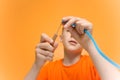 Child in an orange T-shirt holds in his hand a tool for twisting paper thin strips of quilling technique