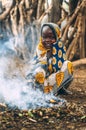 TOPOSA TRIBE, SOUTH SUDAN - MARCH 12, 2020: Child in ornamental cloth smiling and looking at camera while sitting on haunches near