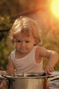 Child outdoor. Portrait of smiling baby boy with blonde curly hair in white underwear holding kitchen utensil Royalty Free Stock Photo