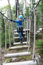 Child overcoming swinging logs obstacle in adventure park