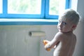 Child paint walls with roller. Cute boy helps to make home repairs. Authentic photo