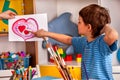 Child painting heart in art school class. Mother day holiday.