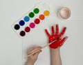 Child painting her hand with red paint and paintbrush. Finger painting or art therapy for children Royalty Free Stock Photo