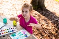 Child painting on paper outdoors on picnic table. Royalty Free Stock Photo