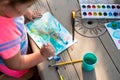 Child painting on paper outdoors on picnic table. Royalty Free Stock Photo