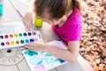 Child painting on paper outdoors on picnic table. Royalty Free Stock Photo