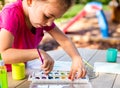 Child painting on paper outdoors on picnic table. Royalty Free Stock Photo