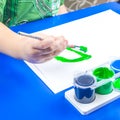 Child is painting a picture with tempera paints