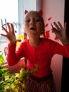 Child painting pumpkin on window preparing celebrate Halloween. Little kid draws decorates room interior with paper bats