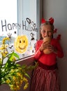 Child painting pumpkin on window preparing celebrate Halloween. Little kid draws decorates room interior with paper bats