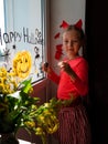 Child painting pumpkin on window preparing celebrate Halloween. Little kid draws decorates room interior with paper bats