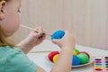Little girl paints blue easter egg Royalty Free Stock Photo