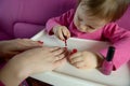 The child paints the nails of his mother with varnish