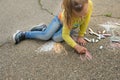 Child paints outdoors. Little girl drawing colored chalk on the asphalt . Creative development of children Royalty Free Stock Photo